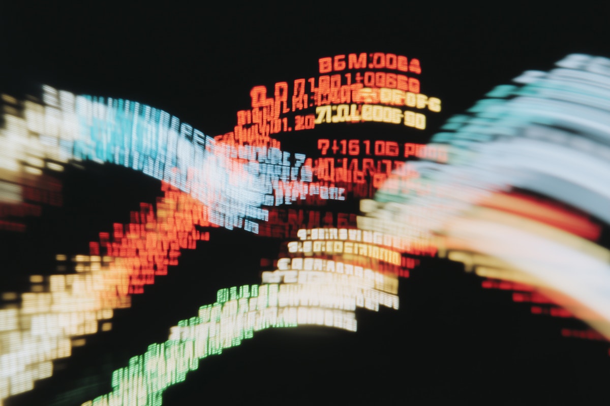 Abstract motion blur of colorful digital text and numbers on a dark background, evoking a futuristic and tech-inspired aesthetic.